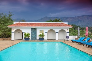 The outdoor pool and its arched pavilion under a sunset sky, blue loungers along the terrace.
