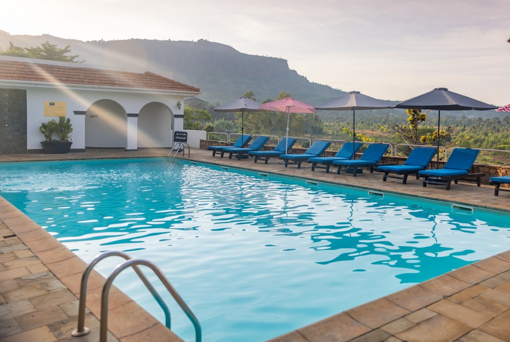 The main swimming pool in the afternoon, blue loungers ranged along one side and the escarpment on the skyline.