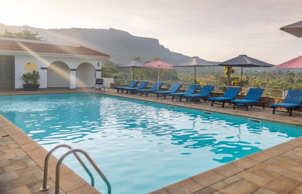The swimming pool at first light, loungers and parasols along the terrace and the escarpment filling the horizon.