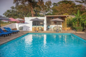 The swimming pool and its paved terrace with loungers and parasols, hills beyond.