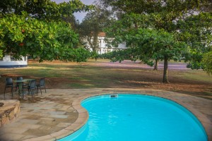 The swimming pool and its paved terrace with loungers and parasols, hills beyond.