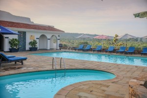 The swimming pool and its paved terrace with loungers and parasols, hills beyond.