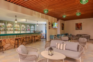 The open-sided poolside bar under a timber ceiling, with cane seating and low tables.