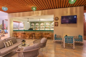 The open-sided poolside bar under a timber ceiling, with cane seating and low tables.