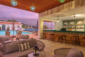 The open-sided poolside bar under a timber ceiling, with cane seating and low tables.