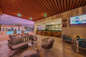 The open-sided poolside bar under a timber ceiling, with cane seating and low tables.