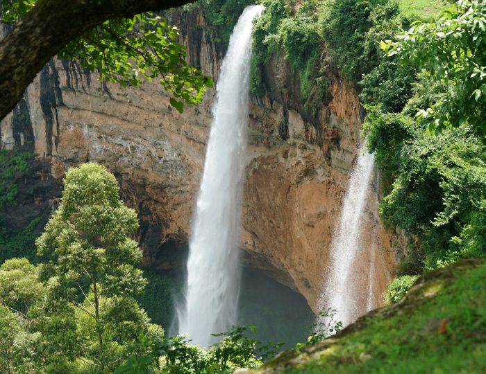 Two waterfalls dropping from a curved cliff into forest at Sipi, eastern Uganda.